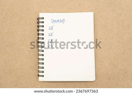 Top view of notebook with handwritten Checklist text. Checklist concept, checklist box with red checkmark.