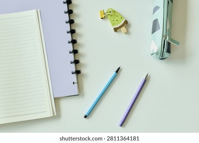 Top view of notebook, planner, pens, pencil case, and bookmark arranging organized study or work setup. Suitable for education planning, productivity, stationery, or back to school marketing