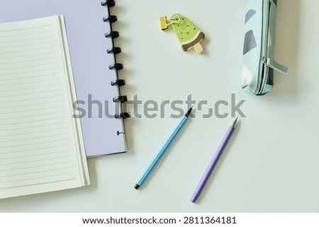 Top view of notebook, planner, pens, pencil case, and bookmark arranging organized study or work setup. Suitable for education planning, productivity, stationery, or back to school marketing