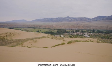 Top View Of Oasis In Desert. Action. Beautiful Small Oasis With Small Town In Desert Area. City With Oasis In Desert On Background Of Mountain Horizon