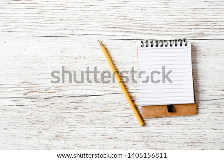 Top view objects yellow pensil and small notebook on wood nature background isolated, short list and education concept, sensitive focus.