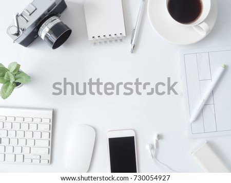 top view of office desk work space with coffee cup, notebook, plastic plant, smartphone, graphic tablet on white background with copy space, graphic designer, Creative Designer concept.