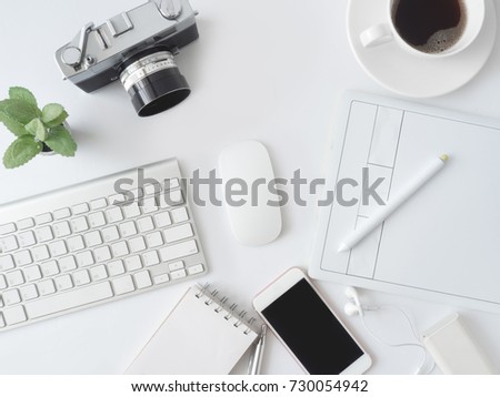 top view of office desk work space with coffee cup, notebook, plastic plant, smartphone, graphic tablet on white background, graphic designer, Creative Designer concept.