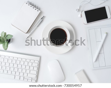 top view of office desk work space with coffee cup, notebook, plastic plant, smartphone, graphic tablet on white background, graphic designer, Creative Designer concept.