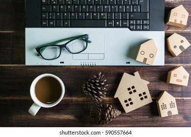 Top view of office stuff with laptop coffee cup and wooden house toy on wooden table.Concept workplace.Real estate concept, New house concept, Finance loan business concept
