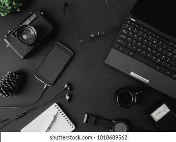 top view office table concept with coffee cup, retro camera, notebook, glasses, laptop and smartphone on black table background - Shutterstock ID 1018689562