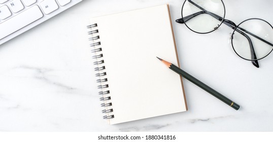 Top view of office table desk cozy work concept with keyboard, notebook, pencil, eyeglasses and coffee on bright marble white background. - Shutterstock ID 1880341816