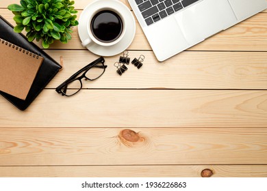 Top view office table desk. Workspace with blank, office supplies, pencil, green leaf, and coffee cup on wood background.