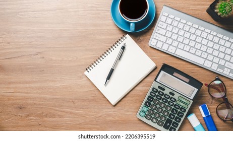 Top View, Office Wooden Desk With Keyboard, Notebook, Pen, Eyeglass, Calculator And Cup Of Coffee, Copy Space, Mock Up.