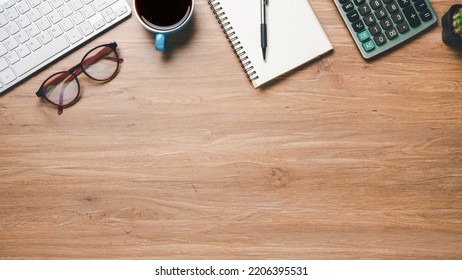 Top View, Office Wooden Desk With Keyboard, Notebook, Pen, Eyeglass, Calculator And Cup Of Coffee, Copy Space, Mock Up.