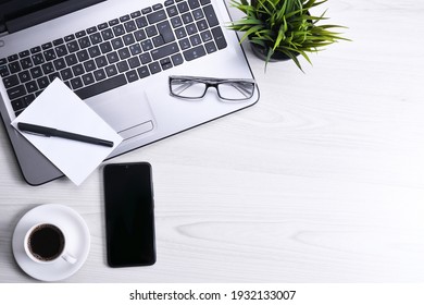 Top view of office work space, wooden desk table with laptop notebook,keyboard,eyeglasses,phone and cup of coffee.With a copy space, flat lay.Mock up.