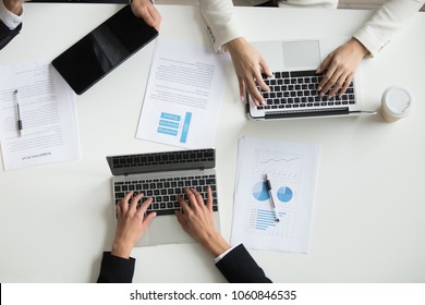 Top View Of Office Workers Typing At Laptop, With Smartphone And Handouts Around During Board Meeting. Marketing Analysis Financial Team Cooperating, Discussing Business Ideas In Coworking Space.