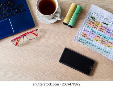 Top View Of Office Workspace Desk With Laptop, Coffee Cup, Eyeglasses, Highlighters, Smartphone And Weekly Calendar With Tasks. Time Management And Time Blocking Technique For Productivity.