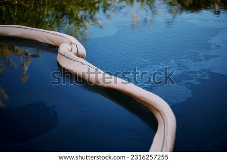 A top view of oil absorbent netted boom on the surface of Isar river in Bavaria, Germany