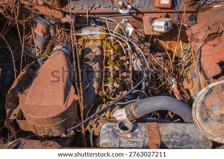 Top view of old engine with heavy corrosion, wires and mechanical elements covered with dirt and moss.