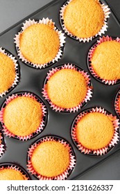 Top View Of Old Fashioned Delicious Sponge Cake Muffins Baked Using Grandma's Recipe In Pink Paper Wrappers On Cupcake Tin