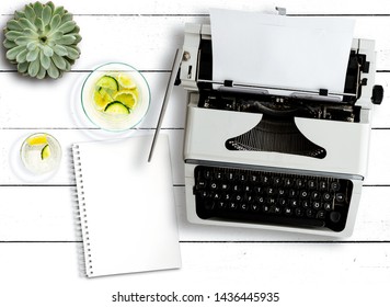 Top View Of Old Typewriter, Succulent Plant, Water Carafe And Notepad On Rustic White Wooden Table