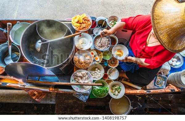 Top view old woman cooking Thai noodle soup Tom Yam\
style on Thai tradition boat in local floating market, Famous\
traditional Thai street food for tourist people travel Bangkok\
Thailand, Tasty Asia