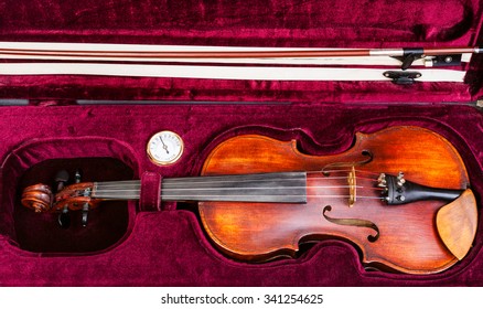 top view of old wooden violin with bow in red velvet case