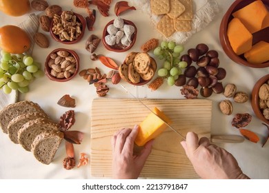 Top View Of An Older Woman's Hands Cutting Pumpkin, Table With Nuts, Grapes And Figs.