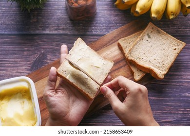 Top View Of Omen Hand Spreading Butter On A Bread 