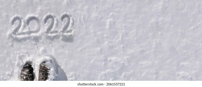 top view on 2022 hand written on the snow with hiker foot in panoramic size 