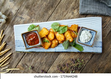Top view on appetizer snacks deep fried chicken nuggets with sauce on the wooden table, horizontal