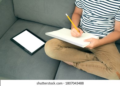 Top view boy writing drawing   using his tablet while doing homework  Studying online during quarantine  online training classes personal education plan concept  Back to school  Mockup