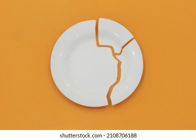 Top View On Broken Circle White Plate On Yellow Background. The Plate Broke Into Three Pieces.