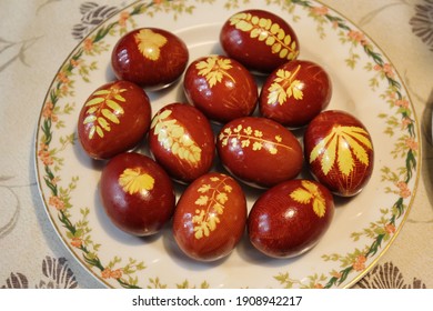 Top view on brown easter eggs dyed in onion husks with different yellow leaves on a plate