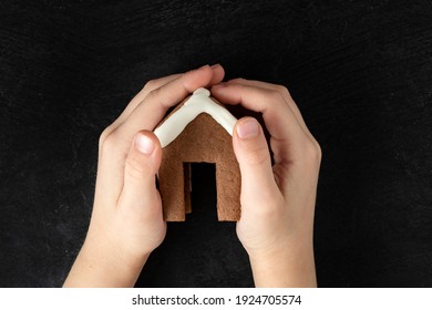 Top View On Child Hands Holding Gingerbread House. Top View, Black Background.