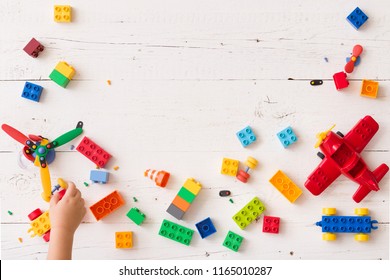 Top view on child's hand playing with multi-color plastic bricks at the table. Toddler having fun and building out of bright constructor bricks. Early learning. Developing toys