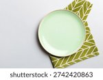 Top view on colored background empty round green plate on tablecloth for food. Empty dish on napkin with space for your design.