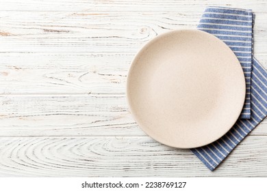 Top view on colored background empty round white plate on tablecloth for food. Empty dish on napkin with space for your design. - Shutterstock ID 2238769127