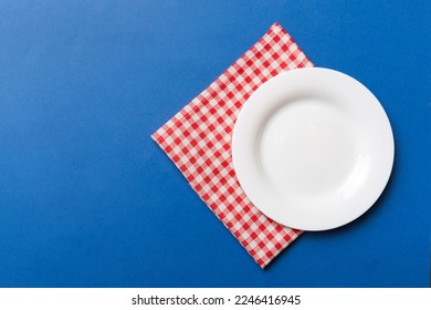 Top view on colored background empty round white plate on tablecloth for food. Empty dish on napkin with space for your design. - Shutterstock ID 2246416945