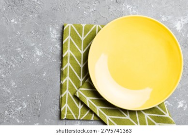 Top view on colored background empty round yellow plate on tablecloth for food. Empty dish on napkin with space for your design.
