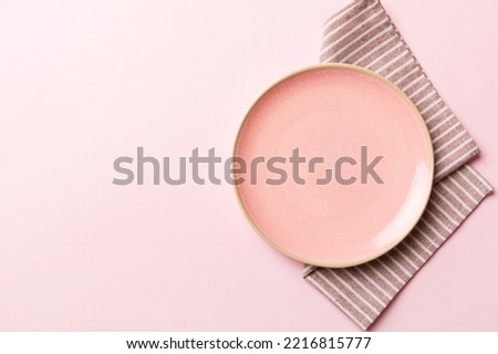 Top view on colored background empty round pink plate on tablecloth for food. Empty dish on napkin with space for your design.