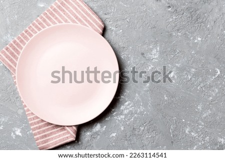 Top view on colored background empty round pink plate on tablecloth for food. Empty dish on napkin with space for your design.