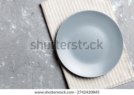 Top view on colored background empty round gray plate on tablecloth for food. Empty dish on napkin with space for your design.