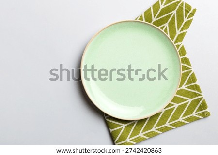 Top view on colored background empty round green plate on tablecloth for food. Empty dish on napkin with space for your design.
