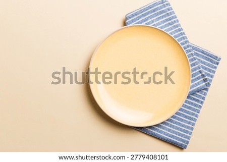Top view on colored background empty round yellow plate on tablecloth for food. Empty dish on napkin with space for your design.