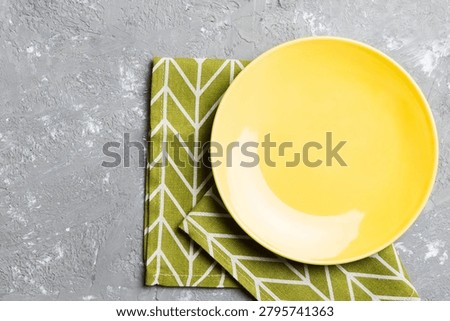 Top view on colored background empty round yellow plate on tablecloth for food. Empty dish on napkin with space for your design.