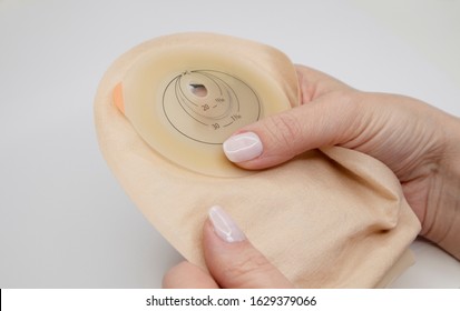 Top view on colostomy bag needed after colostomy surgery - colon cancer treatment. Ostomy bag with filter in skin color. Medical theme. Stoma bag in woman’s hands.