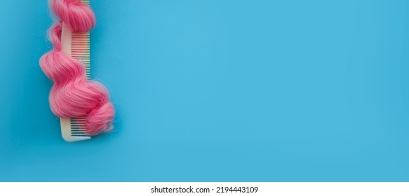 Top View On The Comb In Curls Of Bright Pink Hair. On A Bright Blue Background. Banner With A Copy Of The Site.