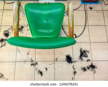 Top View On The Corner Of The Green Barber Chair In The Barber Shop. Hair On The Floor In A Barber Shop.