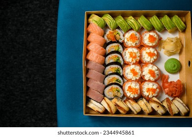 Top view on different sushi rolls with salmon, avocado and smocked eel on blue sofa on black carpet. Online order. Space for text - Powered by Shutterstock