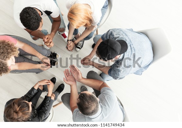 Top view on difficult youth talking\
to a therapist while sitting in a circle during\
meeting
