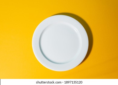 Top View On An Empty White Platter On Yellow Background. Plate Mockup For Gourmet Dish. Element For A Menu Of Restaurant.