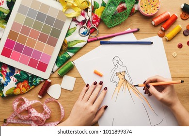 Top View On Fashion Designer At Work. Female Hands Drawing Clothes Sketch At Her Creative Workspace And Using Digital Tablet With Color Swatches On Screen, Top View