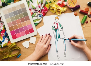 Top View On Fashion Designer At Work. Female Hands Drawing Clothes Sketch At Her Creative Workspace And Using Digital Tablet With Color Swatches On Screen, Top View